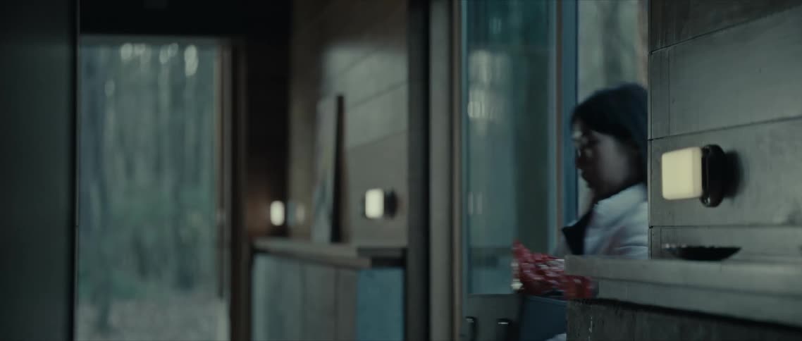A woman walks through a sliding door holding a box of items