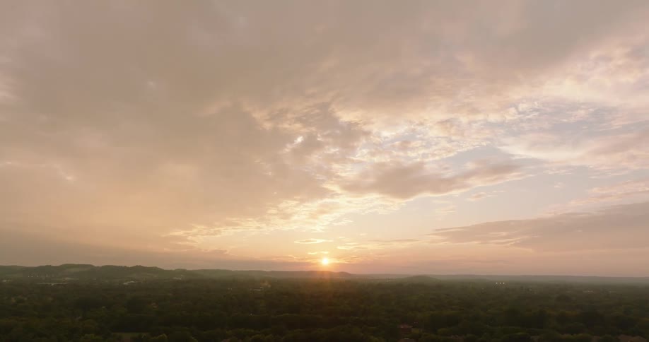 A church sits near a large suburb as the sun shines low in the sky