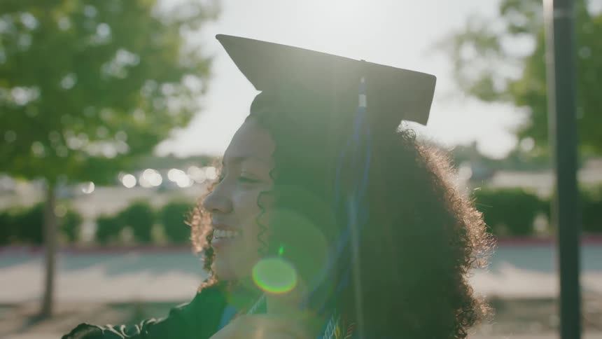 Profile of a female graduate moving her tassel from right to left side of her cap