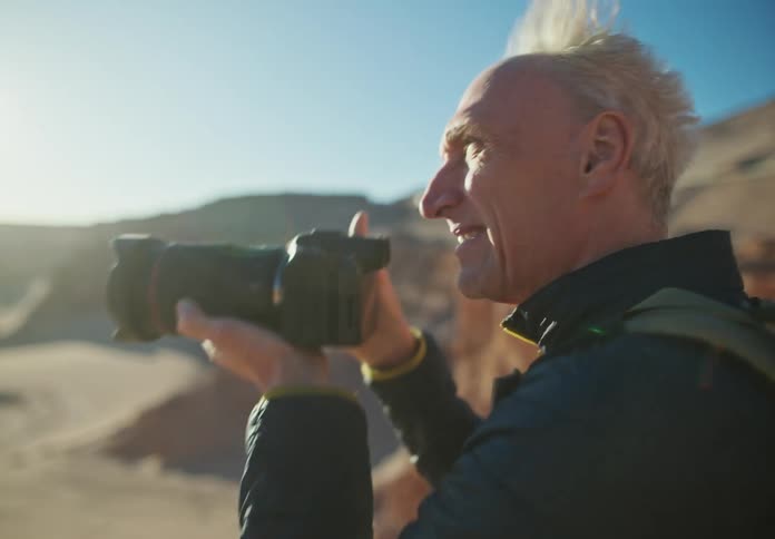 Man with a professional photo camera taking photos in a natural environment