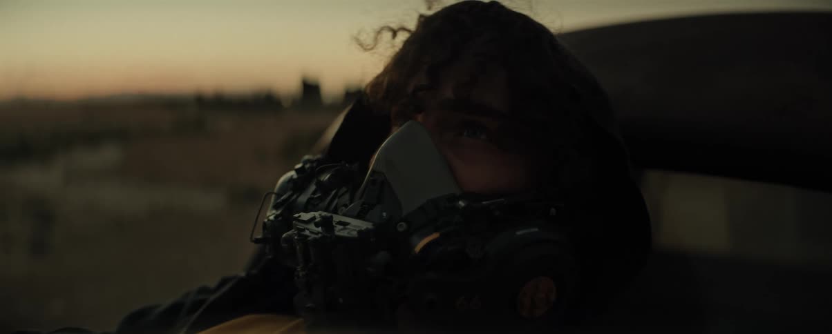 Man wearing a breathing mask lies on a vehicle while red tints the horizon