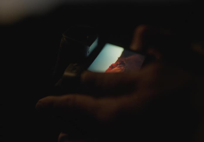 A human hand looking at photos taken on the screen of a camera showing mountain landscapes
