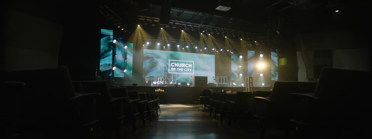 Empty auditorium with organized chairs and a stage lit with a big screen