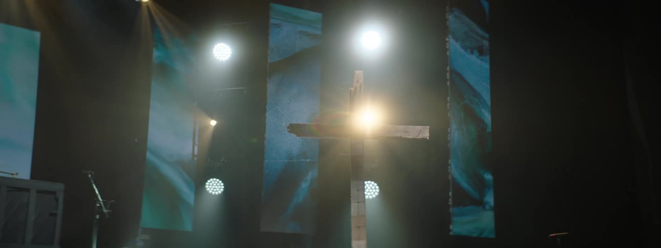 Wooden cross highlighted by lights on a stage located in an auditorium