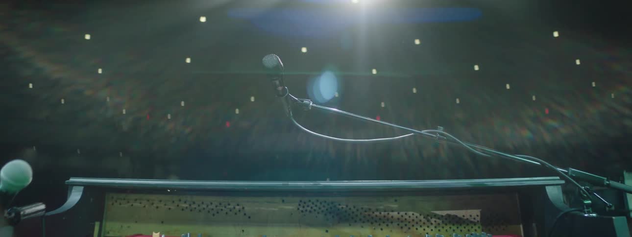Piano with microphone on a stage and an empty auditorium