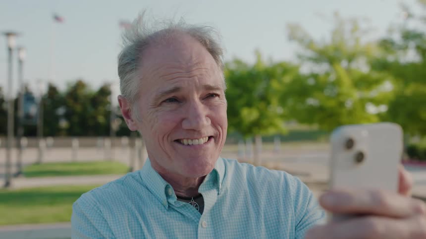 Portrait of an elderly man holding a cell phone in front of his face and talking