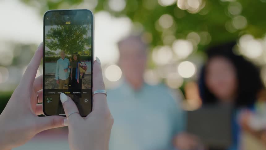 Pair of a womans hands holding an iphone and taking photos of two people