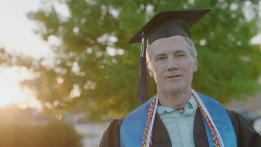 A man is smiling while wearing a cap and gown