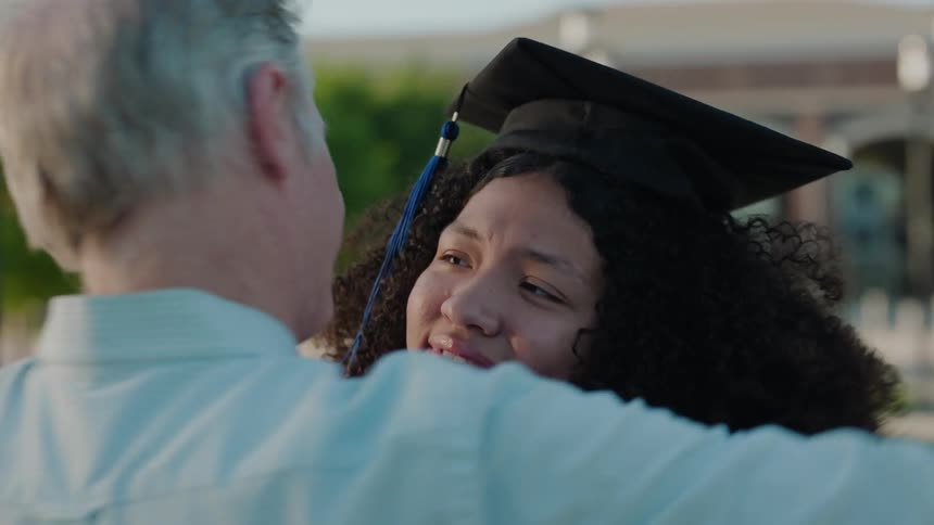 Father hugging his daughter after taking a picture of her holding her diploma