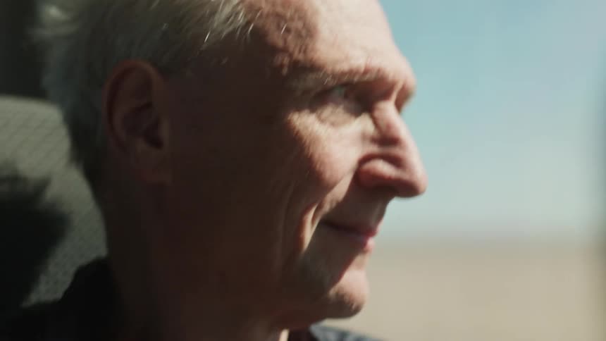 Elderly gentleman sitting in a moving vehicle with facial expression of happiness
