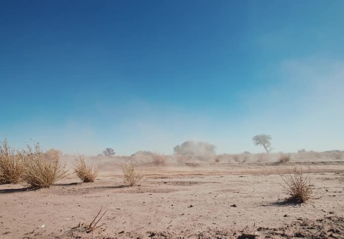 Small white jeep speeding across the desert creating a dust cloud