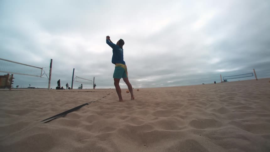 Man jumping and playing volleyball on the beach sand