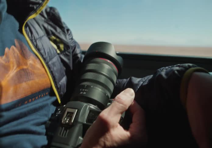 Closeup of a mans hand inside a moving car holding a professional camera
