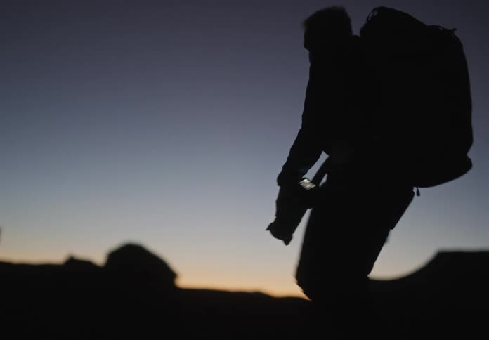 Silhouette of a photographer carrying a professional camera in a backpack walking in a natural environment