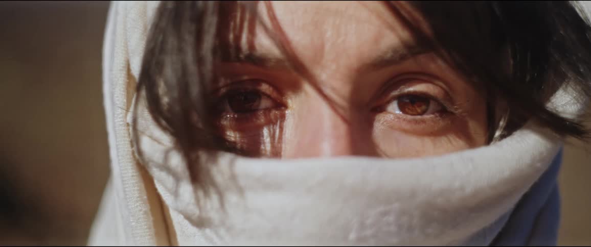 Close up of the eyes of a woman wearing a white scarf over her face