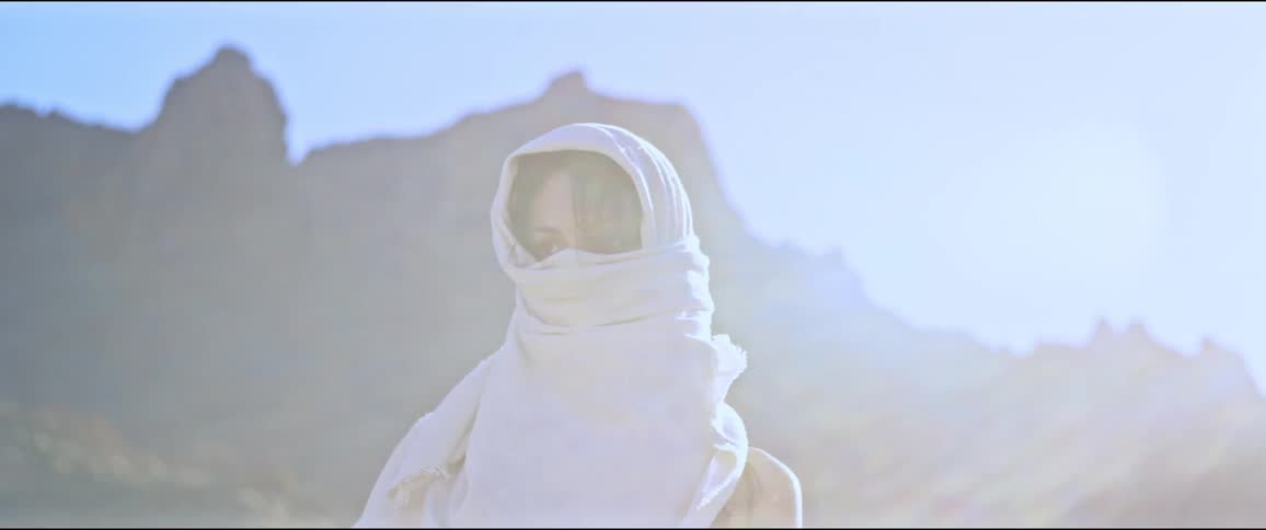 Woman with a scarf on her face and head in a natural environment with mountains in the background