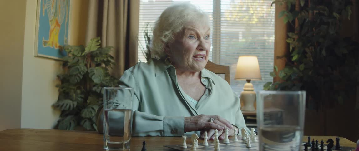 A woman looks slightly angry as she speaks to another person over a chessboard