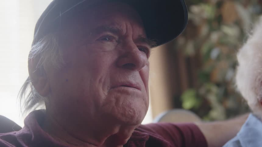 Close up of an elderly man having a conversation with his wife on the couch