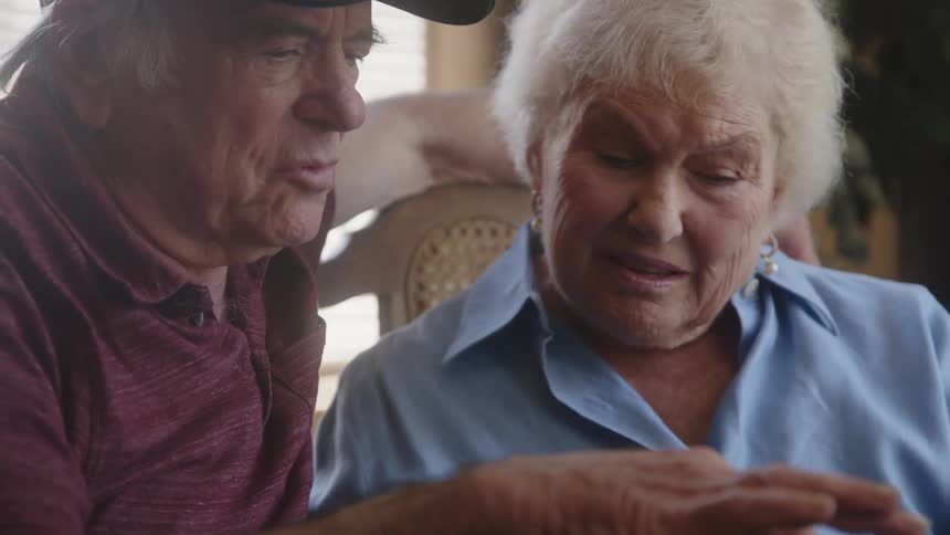 An elderly couple sitting at home looking at photo albums