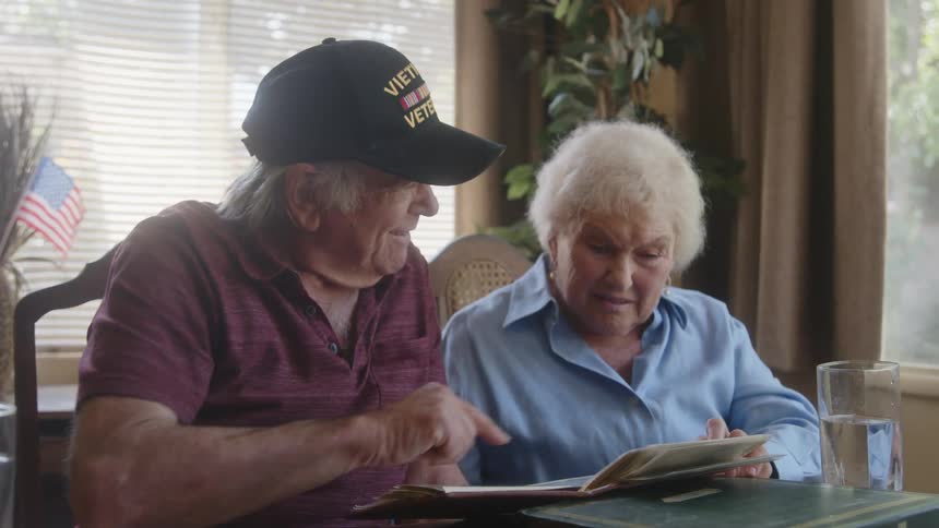 Elderly couple sitting at a table looking at a photo album