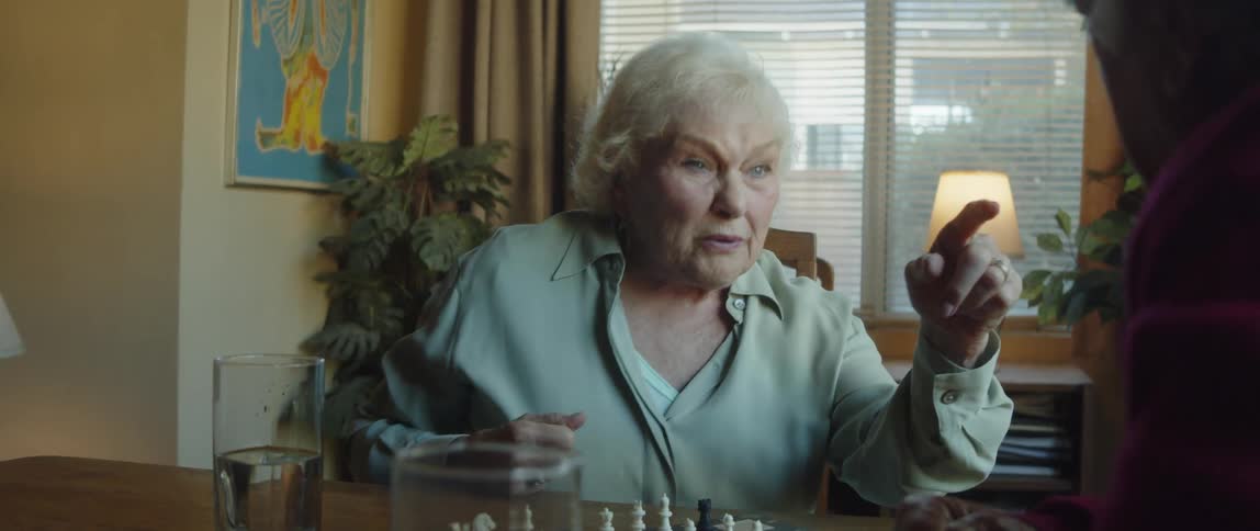 An elderly woman gestures while having a conversation at home