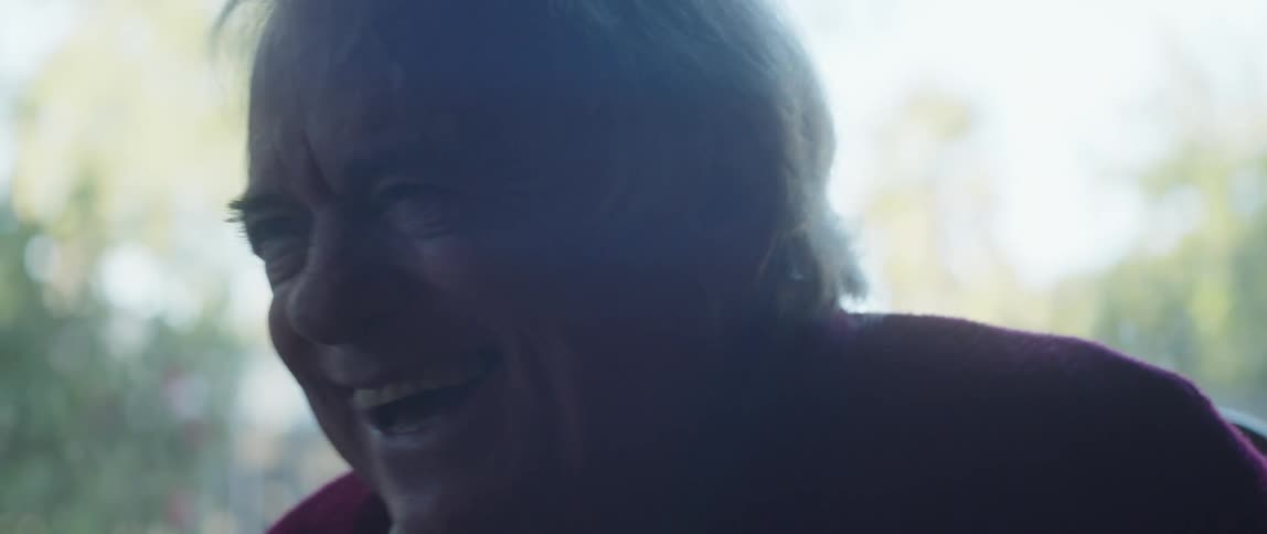 The face of an elderly man who is cackling with laughter