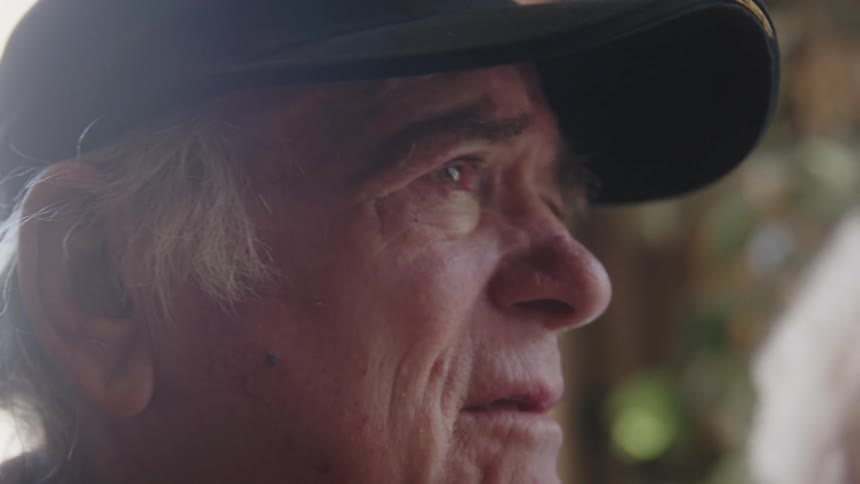 Old man wearing a veterans hat having a conversation