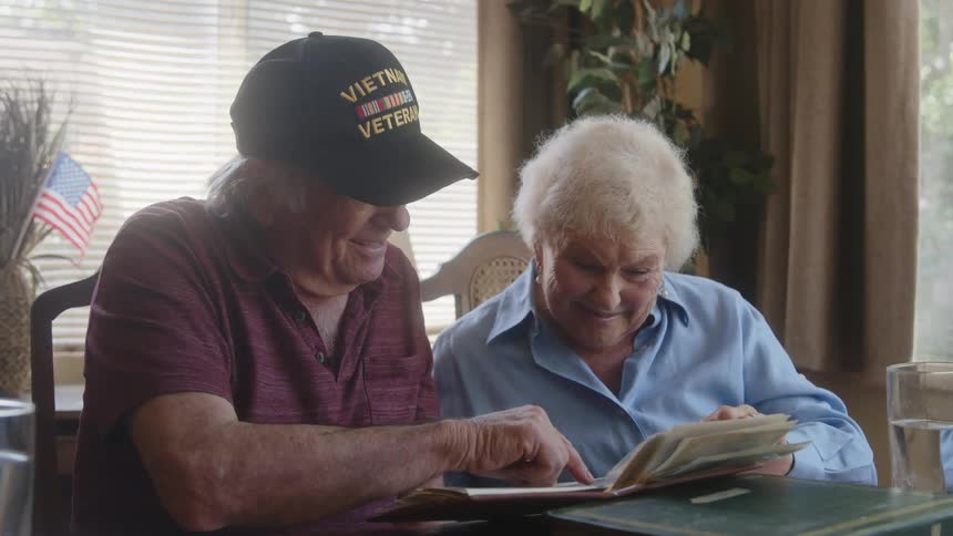 An elderly couple have fun looking at a photo album at home