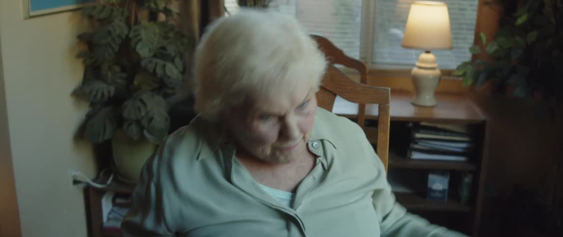 A lady sitting on a chair is punching the air while talking