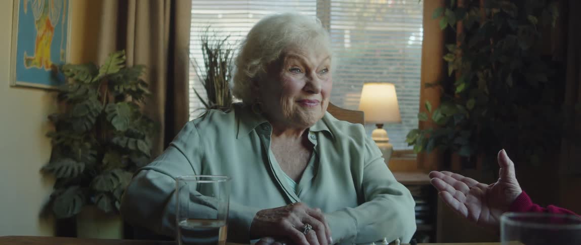 An elderly couple sitting at the dinner table at home talking to each other