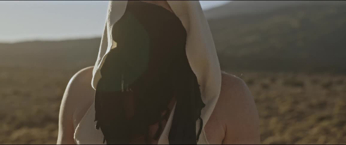 A man with his face covered with a cloth in a desert