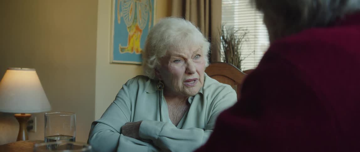 An elderly couple sitting at the dinner table at home talking to each other