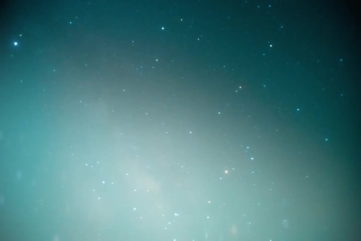 A view from space of a starry sky and there is a glow coming from the bottom