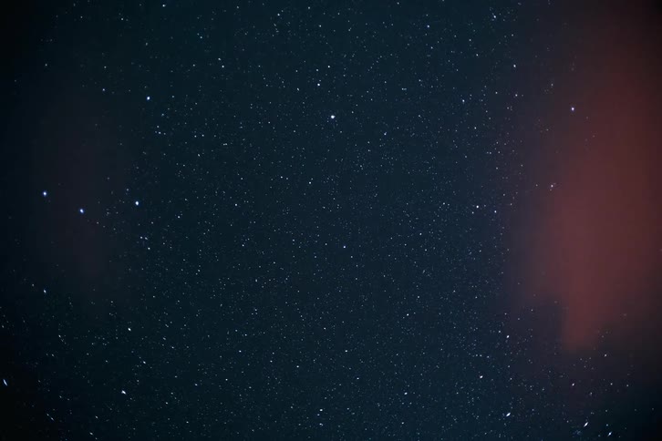 View of the night sky with stars and clouds passing by
