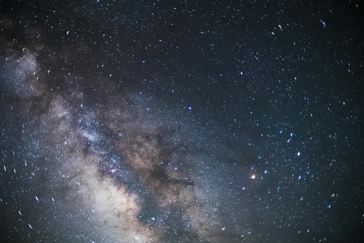 View of a night sky with the milky way and clouds passing by