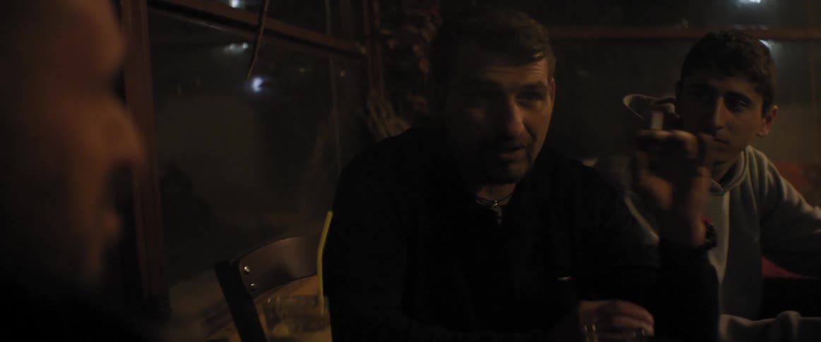 A group of men sitting and talking outside at night
