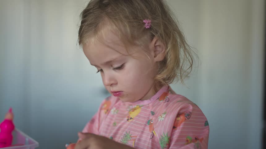 A young girl looks a bit off as she unscrews a paint bottle