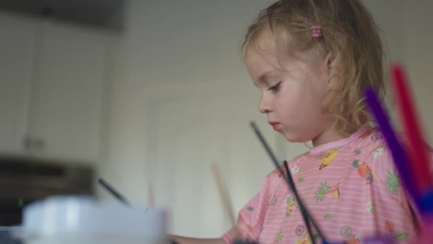 Portrait of a little blonde girl using a paint brushes