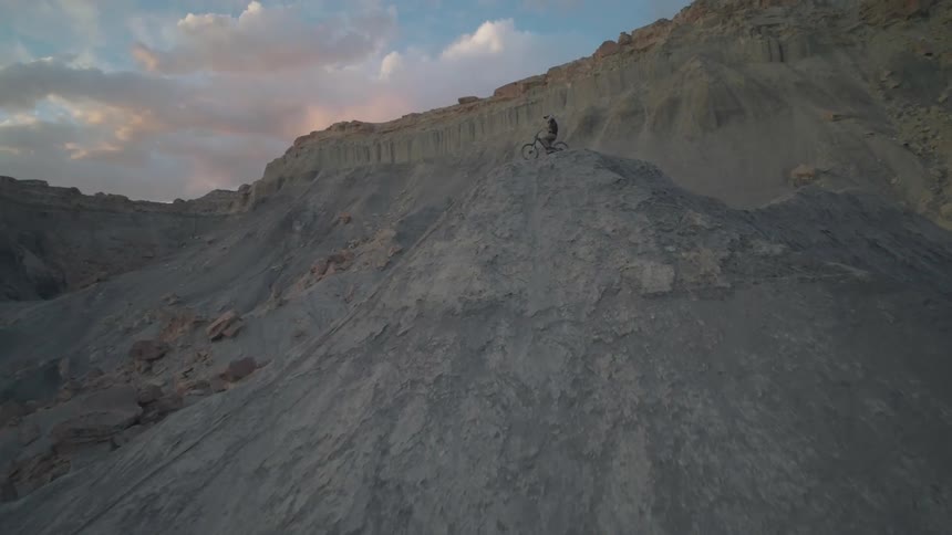 Man in helmet on top of a mountain bike on the peak of a rocky mountain cliff