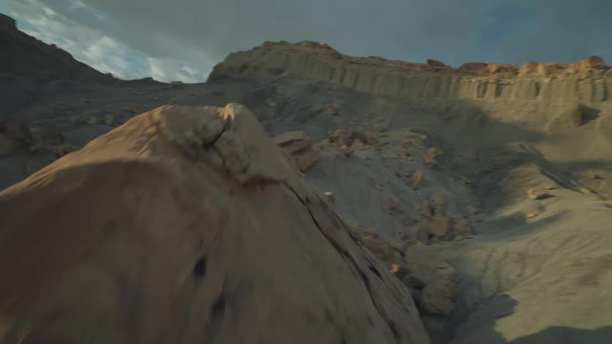Rocky dunes near mountains under a blue and cloudy sky