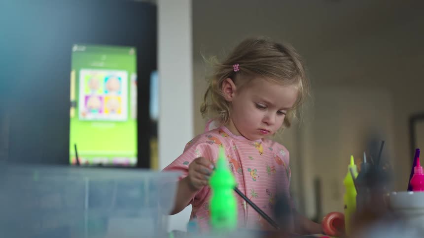 Little blonde girl playing with a paint brush