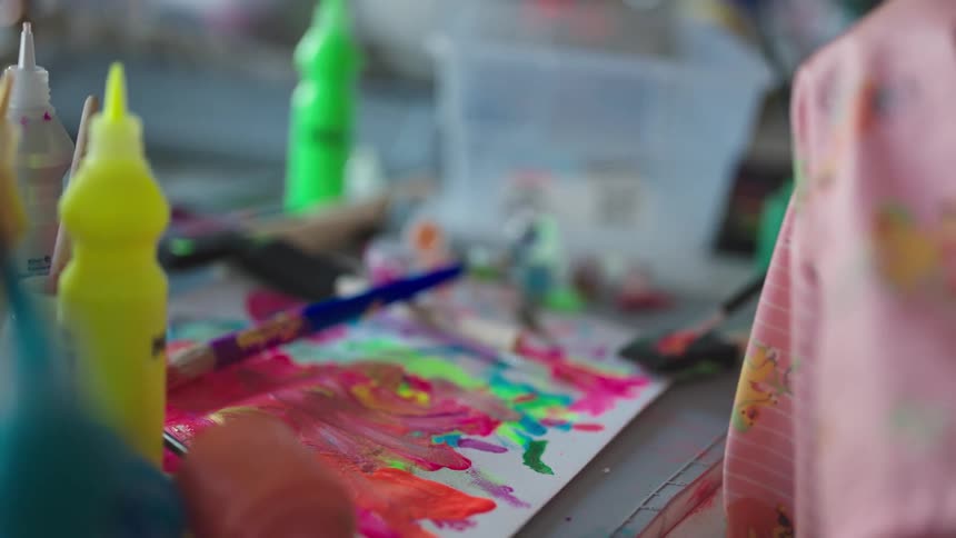 Little girls hand holding a brush and painting a blank sheet of paper