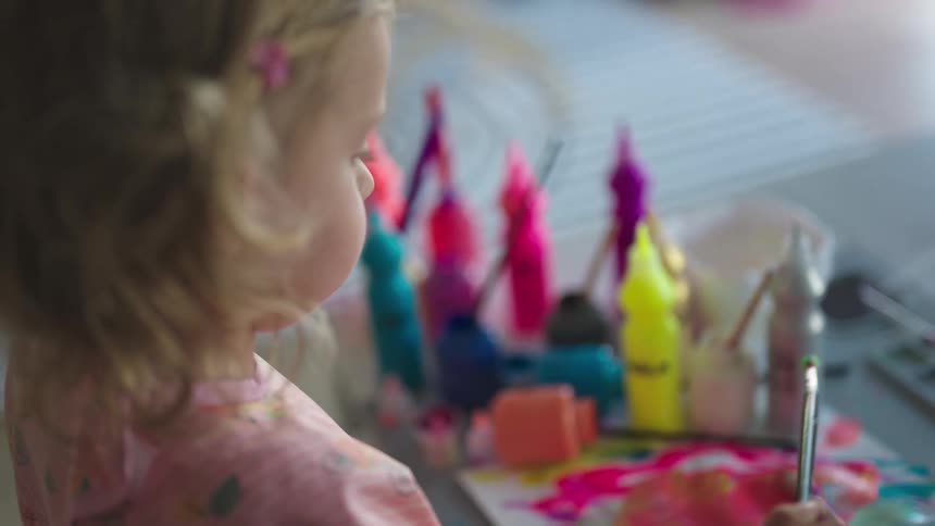 Little girl with paintbrush playing paint