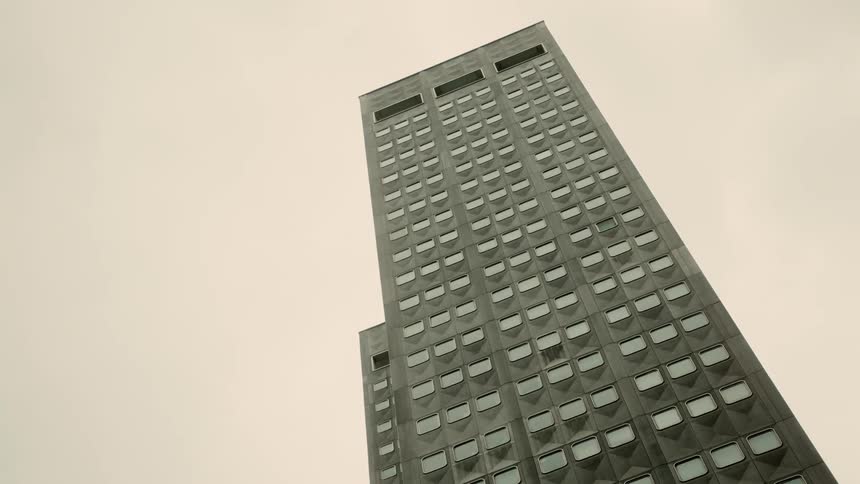 A tall building with a gridlike pattern of windows viewed from a low angle against an overcast sky