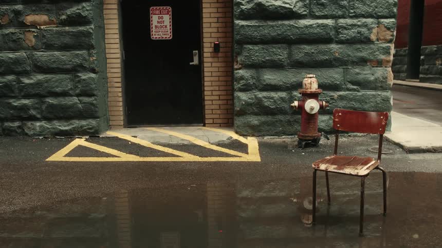 Entrance to a building with blue stone walls a black door and a laod chair outside in a puddle of water