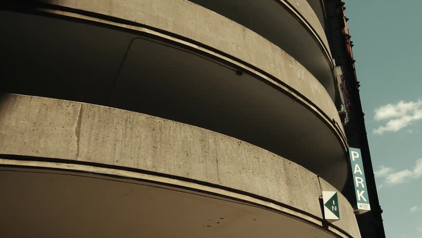 A curved multi level concrete parking lot featuring a sign that reads park
