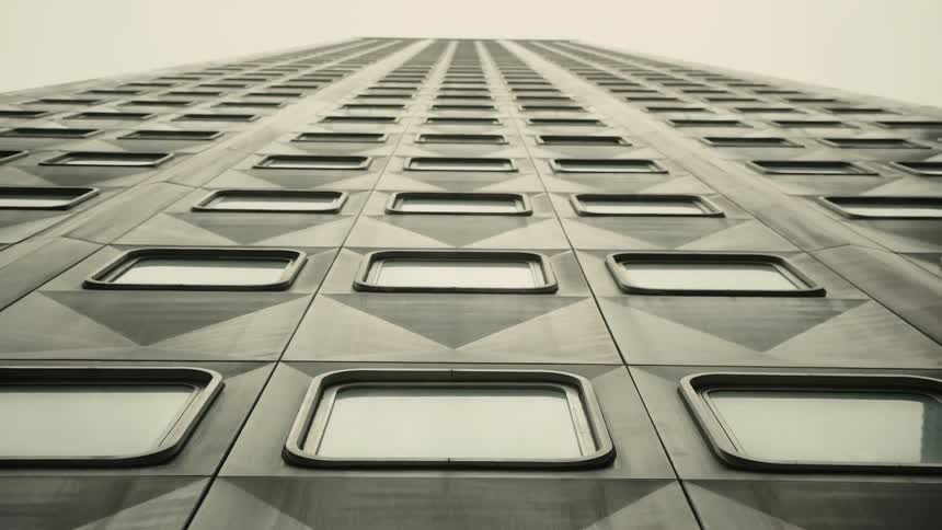Upward view of a large modern building against a cloudy sky
