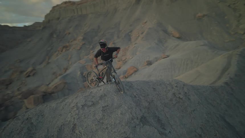 Man with helmet and his mountain bike on the peak of a rocky mountain
