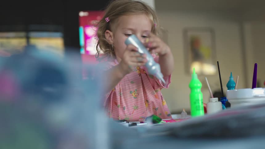 A young girl squeezes silver paint from a bottle