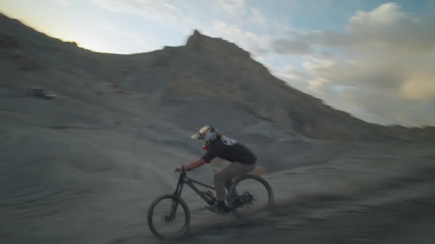 A man does jumps in the desert on his bike